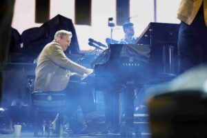 A man playing an acoustic piano onstage.