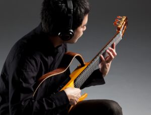 male playing Yamaha SILENT guitar and wearing headphones 
