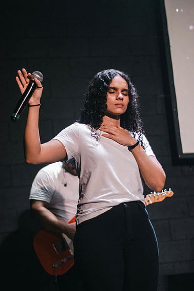 Young church worship leader with hands up while holding microphone