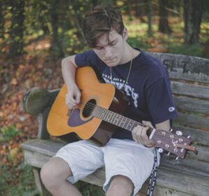 guitar student sitting on bench outdoors