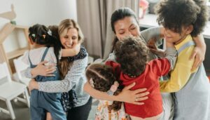 happy elementary students hugging teachers