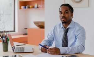 man sitting at desk with papers and an open laptop