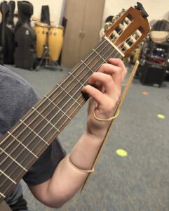 a ruler attached to guitar students left hand with rubberbands