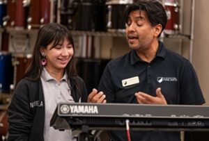 music teacher talking to student in front of keyboard
