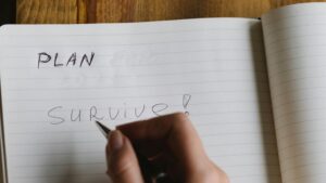writing in notebook "Plan: Survive"