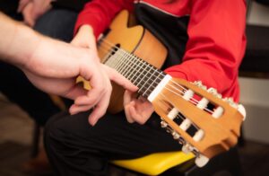 teacher pointing to fretboard of a student's guitar