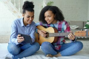 two teens with guitar and tablet