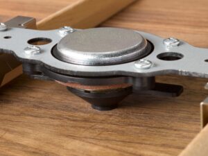 A small round metal device installed on the inside of an acoustic guitar.