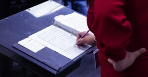 music educator looking at notebook with sheet music