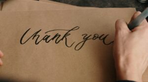 someone writing thank you on craft paper 