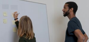 woman and man standing at whiteboard