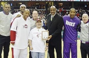 young child holding plague surrounded by pro basketball players including LeBron James