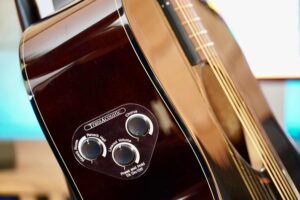 Three small knobs on the top of an acoustic guitar.