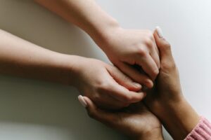 close up of adult hand holding child's hands 