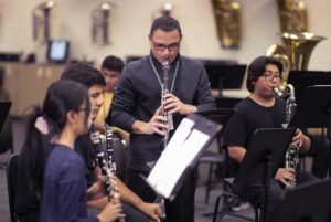 band director playing clarinet with students 