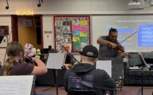 orchestra teacher playing violin along with his students