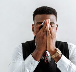 overwhelmed adult holding face in his hands