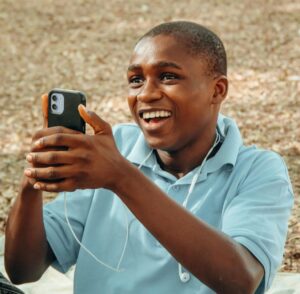 smiling teen holding cell phone and wearing earbuds