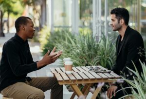 two men sitting at an outdoor table