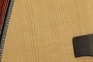 Closeup of the wood grain of the top of an acoustic guitar.