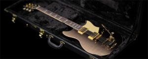 A black electric guitar in an open hardshell case.
