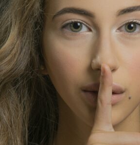 close up of someone holding a finger to their lips 