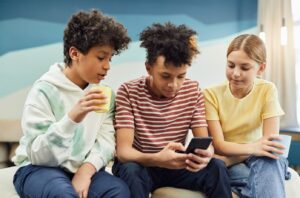 three students sitting together and looking at a phone